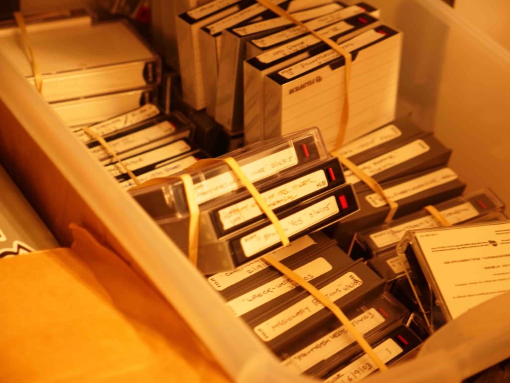 Labeled MiniDV cassettes bundled in a storage bin